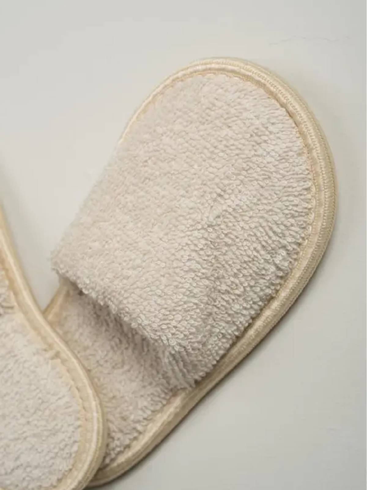 Ayıcık kapüşonlu, krem renkli bebek bornoz takımı; bornoz, panço havlu ve terlikten oluşan 3’lü set, beyaz fonda düz zemin üzerinde.